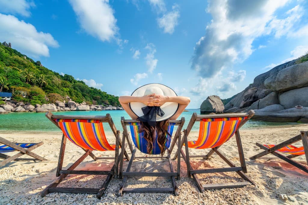 Γυναίκα χαλαρώνει σε ξαπλώστρα σε τροπική παραλία